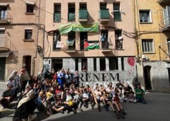 Los miembros de PAHC se sientan fuera del edificio recuperado donde Pablo y Nadia viven en Manresa, Cataluña, el 5 de mayo de 2024, para celebrar el primer aniversario de la sentadilla.