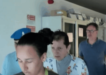 Una persona con una camisa floral escolta por agentes de policía.