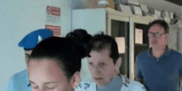 Una persona con una camisa floral escolta por agentes de policía.