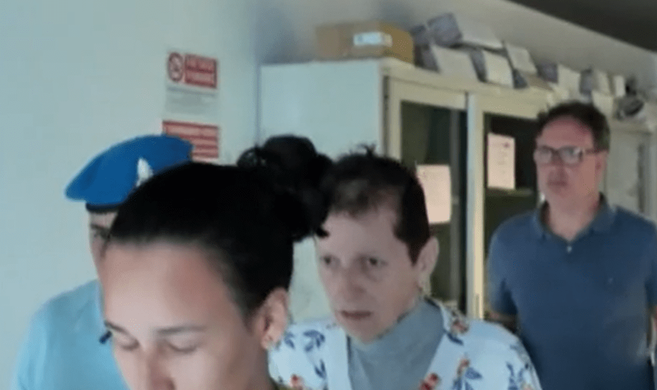 Una persona con una camisa floral escolta por agentes de policía.