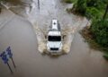 Camión que conduce a través de aguas de inundación en una carretera.