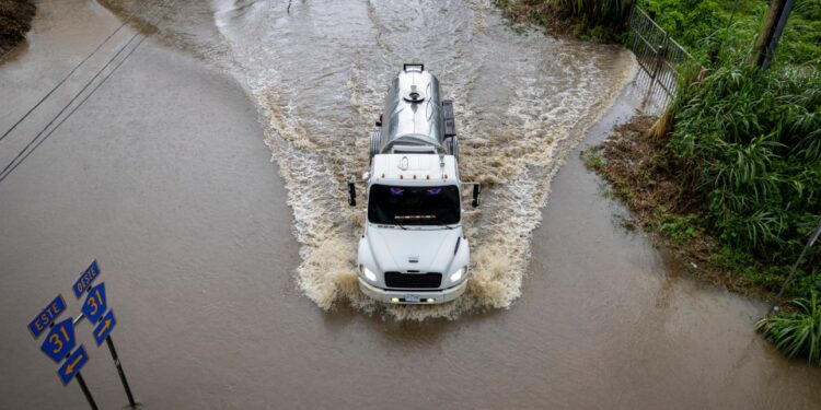 Camión que conduce a través de aguas de inundación en una carretera.