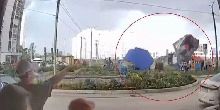 Castillo hinchable con niños adentro levantados en el aire por fuertes vientos.