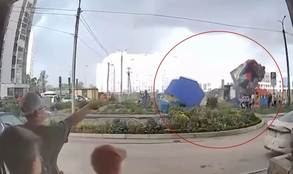 Castillo hinchable con niños adentro levantados en el aire por fuertes vientos.