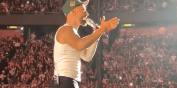 Cantante actuando en el escenario frente a una gran multitud.