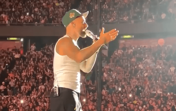 Cantante actuando en el escenario frente a una gran multitud.