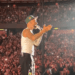 Cantante actuando en el escenario frente a una gran multitud.