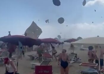 Los amantes de la playa huyen de un tornado que levanta los paraguas de la playa al aire.