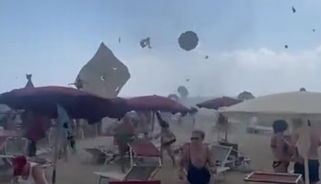 Los amantes de la playa huyen de un tornado que levanta los paraguas de la playa al aire.