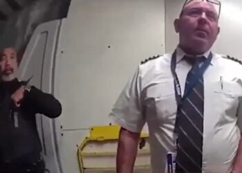 Oficial de policía escoltando a un piloto desde una cabina.