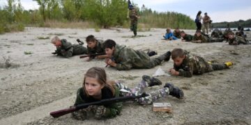 Los estudiantes en uniformes de camuflaje participan en ejercicios de entrenamiento militar.