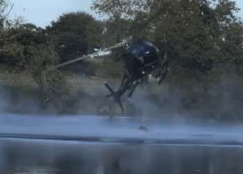 Helicóptero pulverizando agua sobre un lago.