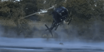 Helicóptero pulverizando agua sobre un lago.