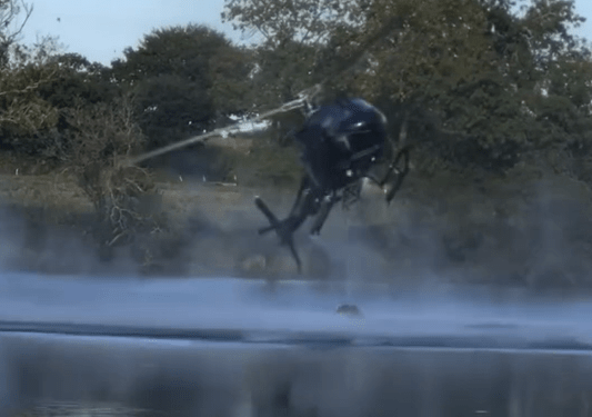 Helicóptero pulverizando agua sobre un lago.