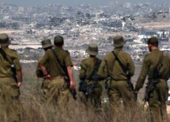 Los soldados israelíes miran los edificios destruidos en la Franja de Gaza mientras están parados en la frontera con el territorio palestino, el 13 de agosto de 2025.