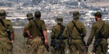 Los soldados israelíes miran los edificios destruidos en la Franja de Gaza mientras están parados en la frontera con el territorio palestino, el 13 de agosto de 2025.