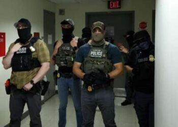 Los oficiales federales que usan revestimientos faciales esperan en un pasillo fuera de una sala del tribunal en el Tribunal Federal de Inmigración de la Plaza de Nueva York dentro del Edificio Federal Jacob K. Javitz en Nueva York.