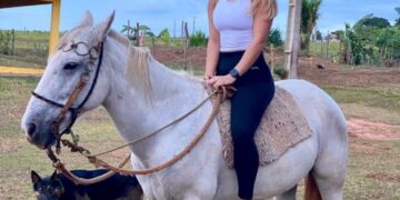 Mujer paseando a caballo con perro.