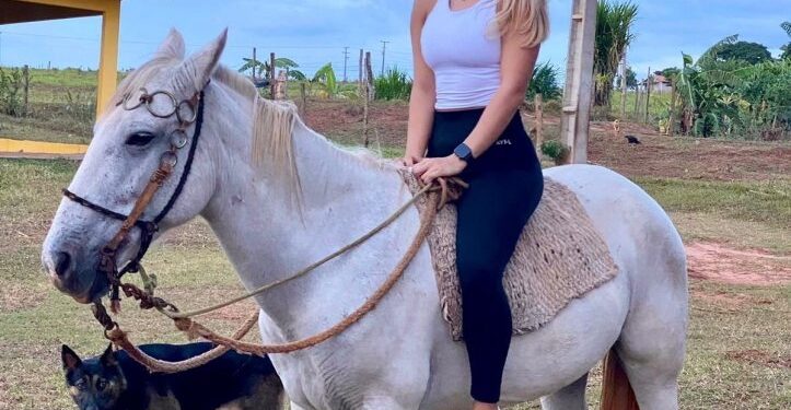 Mujer paseando a caballo con perro.