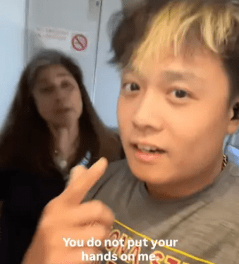 Persona que habla con la cámara, diciendo "No me pones tus manos" con otra persona en el fondo.