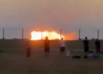 Gente mirando un gran incendio al atardecer.