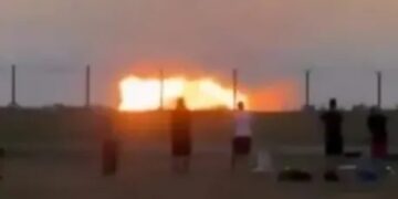 Gente mirando un gran incendio al atardecer.