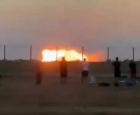 Gente mirando un gran incendio al atardecer.