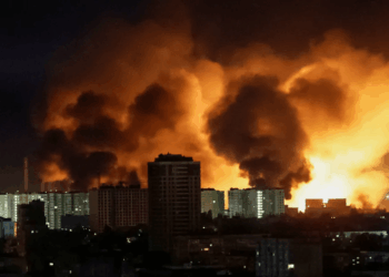 Gran fuego detrás de los edificios de la ciudad por la noche.