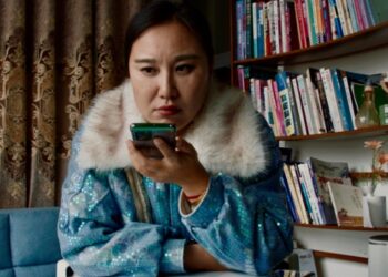 Aún de la película *Mistress Dispeller *, dirigida por Elizabeth Lo. Una mujer usa un teléfono inteligente.