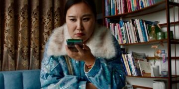 Aún de la película *Mistress Dispeller *, dirigida por Elizabeth Lo. Una mujer usa un teléfono inteligente.