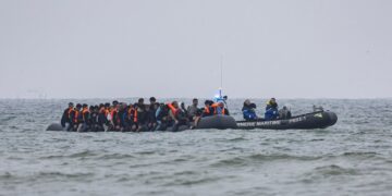 Los migrantes en un bote seguidos por un barco de gendarmería marítimo francés en el Canal de la Mancha.