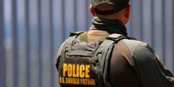 Un agente de la Patrulla Fronteriza se encuentra en el Parque Estatal Border Field con el muro fronterizo estadounidense-México en el fondo el 17 de agosto de 2025.