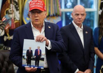 El presidente Trump sosteniendo una foto de él y el presidente Putin.