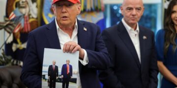 El presidente Trump sosteniendo una foto de él y el presidente Putin.