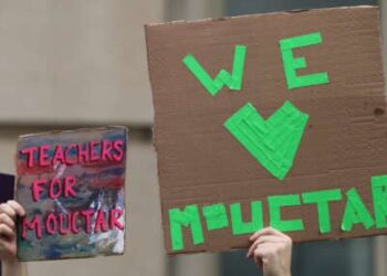 La gente tiene señales mientras los funcionarios de la ciudad de Nueva York hablan en una conferencia de prensa que convoca el lanzamiento del estudiante de secundaria Mamadou Mouctar Diallo el 14 de agosto de 2025 en la ciudad de Nueva York.