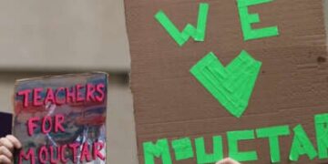 La gente tiene señales mientras los funcionarios de la ciudad de Nueva York hablan en una conferencia de prensa que convoca el lanzamiento del estudiante de secundaria Mamadou Mouctar Diallo el 14 de agosto de 2025 en la ciudad de Nueva York.