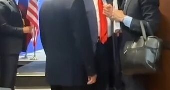 Putin y Trump hablando con otros en un pasillo.