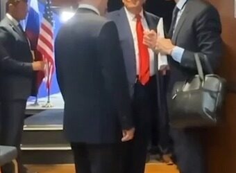 Putin y Trump hablando con otros en un pasillo.