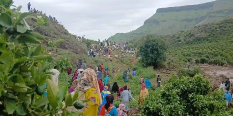 Gran grupo de personas se reunieron en un área montañosa, posiblemente respondiendo a un desastre.