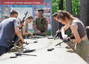 Los niños y adolescentes aprenden a reunir y desmontar rifles con un instructor.