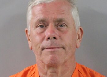 Mugshot de un hombre con un mono naranja.