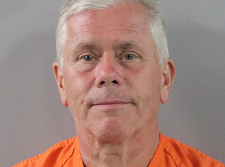 Mugshot de un hombre con un mono naranja.