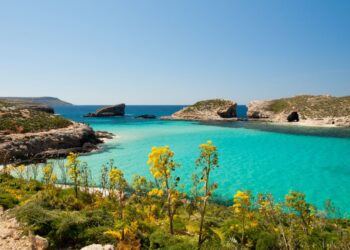 Una vista de las brillantes aguas turquesas de la laguna azul en Comino, Malta. El islote de Cominotto está a la derecha.
