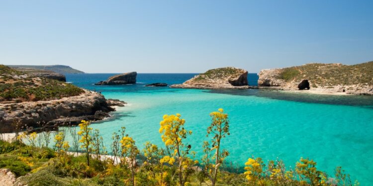 Una vista de las brillantes aguas turquesas de la laguna azul en Comino, Malta. El islote de Cominotto está a la derecha.