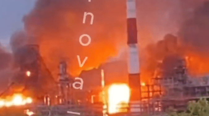 Una planta química en llamas con una gran humo de rayas roja y blanca.