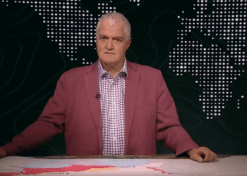 Hombre con una chaqueta rosa que se presenta frente a un mapa mundial.