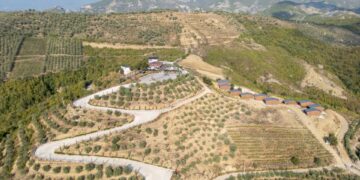 Vista aérea de Solis Farm, un olivo, restaurante y cabañas en una región montañosa de Albania.