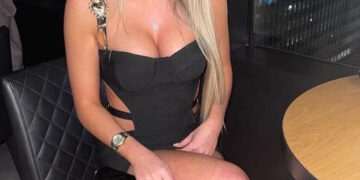 Mujer con vestido negro sentado en una mesa.