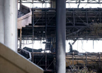 Un hombre de seguridad no identificado camina por el piso en la sede de la Red de Noticias de la República Islámica de Irán (Irinn) en el complejo de televisión estatal de Irán, que fue destruido en huelgas israelíes, en el norte de Teherán, Irán, el 19 de junio de 2025.