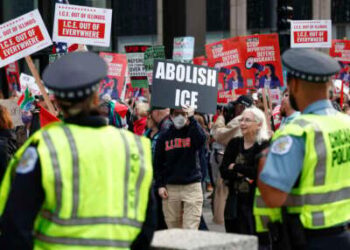Los oficiales de policía observan mientras las personas participan en una manifestación contra el despliegue planificado de tropas de la Guardia Nacional en Chicago